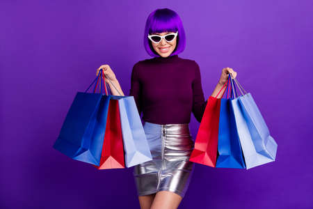 Amazing stylish lady holding packs in hands wear sun specs trendy outfit isolated purple backgroundの写真素材