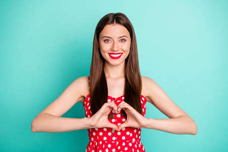 Portrait of lovely girl hsoiwing her figure shape heart with fingers smiling wearing polka dot skirt...