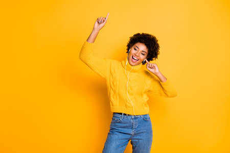 Portrait of her she nice attractive charming lovely cheerful cheery carefree wavy-haired girl having fun listening to music isolated over bright vivid shine vibrant yellow color backgroundの写真素材