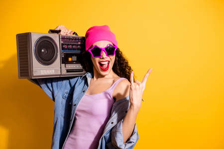 Photo of nice lady with tape recorder on shoulder listening metal song making horns symbol wear casual trendy clothes isolated yellow color backgroundの写真素材