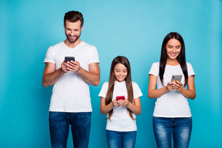 Photo of three family members writing email letters in telephones wear casual outfit isolated blue backgroundの写真素材