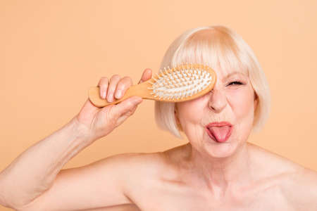 Close-up portrait of her she nice attractive nude naked well-groomed, cheerful cheery positive crazy comic foolish gray-haired lady having fun time isolated over beige backgroundの写真素材