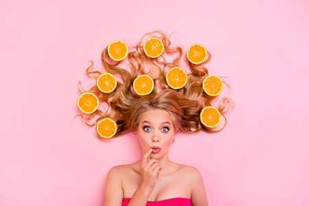 Close up top above high angle view photo beautiful funny funky she her lady, lying down oranges long curly wavy hair wondered interested asking isolated pink backgroundの写真素材