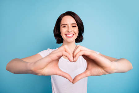 Close-up portrait of her she nice attractive lovely sweet tender confident cheerful cheery girl showing giving heart forever love isolated on bright vivid shine vibrant blue turquoise color backgroundの写真素材