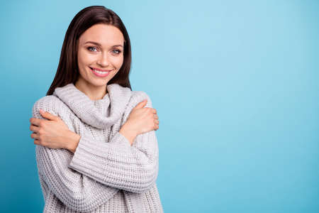 Turned photo of charming content lady hug herself cuddling feel glad, wear white knitted sweater...