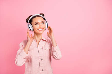 Portrait of charming lady holding headset dreaming looking up wearing, pastel color jacket isolated...