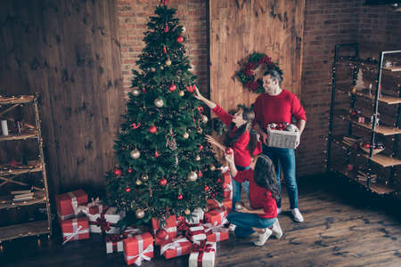 Above high angle full length body size view of three nice attractive cheerful glad family mom dad decorating fir fairy december winter vacation in industrial loft wood brick style interior indoorsの写真素材