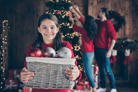Portrait of nice attractive cheerful dreamy preteen girl family mom dad decorating fir tree fairy custom december vacation wintertime in industrial loft wood brick style interior indoorsの写真素材