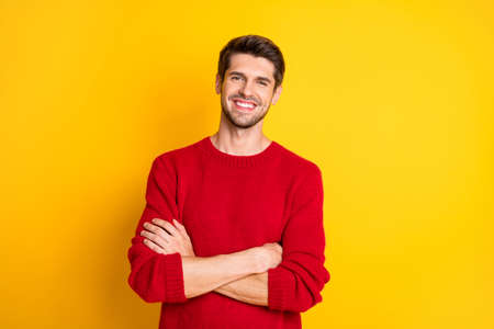 Portrait of charming man with his hands crossed wear red jumper isolated over yellow backgroundの写真素材