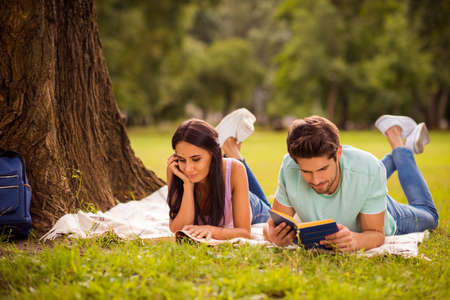 Her she his he nice attractive lovely smart clever focused concentrated best friends spending weekend free spare time on fresh open air lying under tree on veil cover outsideの写真素材