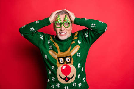 Shocking discounts on X-mas eve night concept. Closeup photo of astonished expressing extreme happiness gentleman with toothy smile holding head with hands isolated vivid color backgroundの写真素材