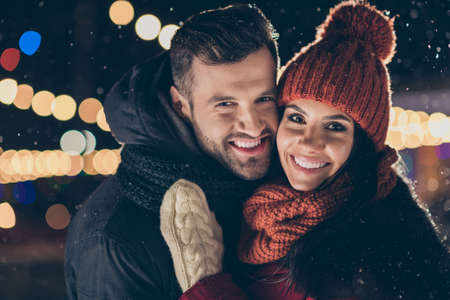 Two affectionate people in central park party at x-mas celebration standing close wear winter...