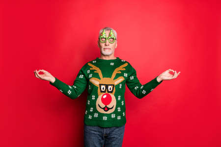 I feel tranquility and serenity inside my soul concept. Everything will be alright. Photo of bearded with closed eyes man in green bright knitted pullover jeans showing om symbol isolated backgroundの写真素材