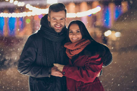Photo of two people visiting central city park at x-mas eve standing close wearing warm winter jackets and scarfs feel holiday spirits outdoorsの写真素材
