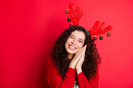 Portrait of cheerful funny funky brunette curly hair girl ready for christmas newyear party wait expect x-mas tradtion her gift present surprise wear trendy sweater isolated red color backgroundの写真素材