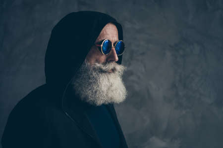 Close-up profile side portrait of his he nice attractive focused content bearded gray-haired man grandfather wearing hoody round specs life lifestyle isolated over concrete industrial wall backgroundの写真素材