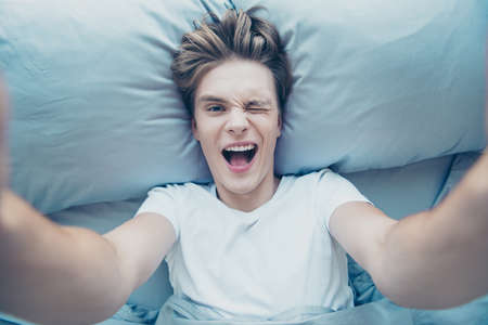 Top above high photo of positive cheerful blonde haired guy influencer take selfie in morning lying...