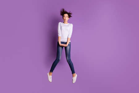 Photo of trendy wavy cheerful shy girl wearing jumping jeans denim footwear kissing you through air...