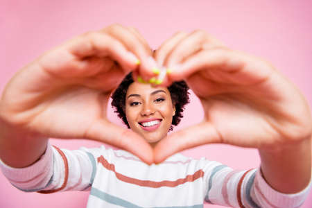 Photo of pretty dark skin lady making fingers heart form holding face inside it in cadre wear...