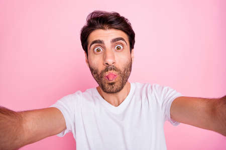 Close up photo of funky funny positive middle eastern man have fun fool on summer vacation show his tongue-out make selfier wear style clothes isolated over pink color backgroundの写真素材