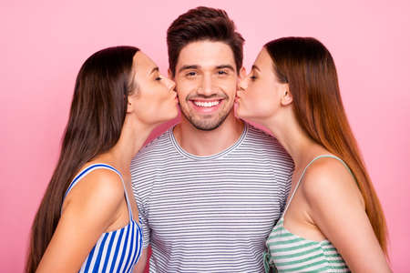 Close up photo of cheerful guy with stubble and girls kissing man closing, eyes wearing striped...