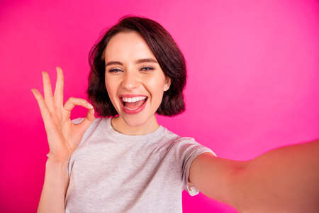 Self portrait of charming cheerful attractive nice cute girlfriend showing you ok sign taking selfie...
