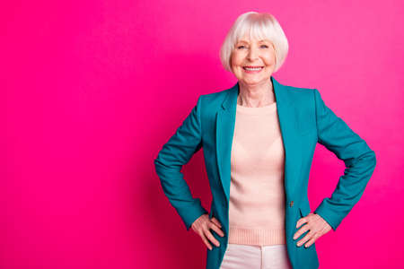 Portrait of her she nice-looking attractive lovely cheerful cheery content gray-haired lady wearing blue green jacket posing isolated over bright vivid shine vibrant pink fuchsia color backgroundの写真素材