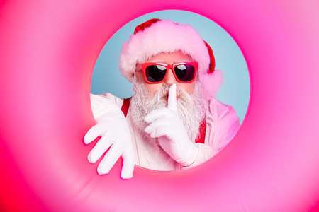 Close-up portrait of his he nice attractive mysterious bearded Santa in inflatable circle showing...