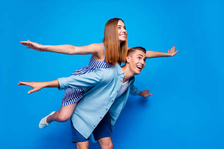 Portrait of his he her she two nice attractive cheerful cheery glad people piggy-backing having fun international tourism isolated on bright vivid shine vibrant blue color backgroundの写真素材
