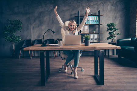 Photo of cheerful smiling entrepreneur having finally finished working on her project and is now able to have some rest sitting in front of her laptopの写真素材
