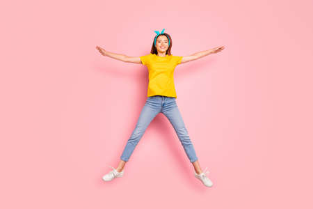 Full body photo of charming, youth holding hands jumping wearing yellow t-shirt isolated over pink...