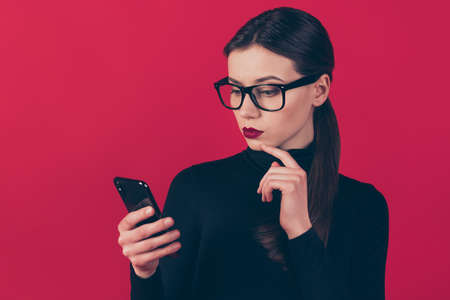Close-up portrait of her she nice-looking attractive gorgeous pretty, minded serious girl using cell online shopping order choose choice isolated on maroon burgundy marsala red pastel color backgroundの写真素材