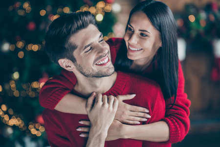 Close up photo of two people romantic dreamy man and woman hug gently, piggyback in house with newyear decoration lights indoors enjoy christmas vacation x-mas holidaysの写真素材