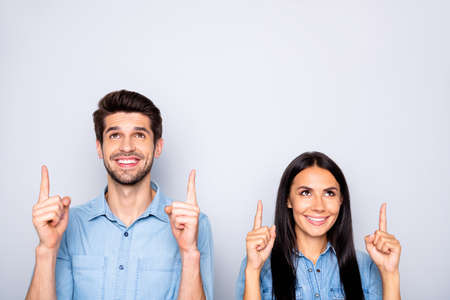 Close-up portrait of nice attractive charming cute cheerful cheery content couple wearing casual pointing forefingers up copy space advertising isolated over light white gray pastel color backgroundの写真素材