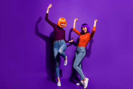 Full length body size view of two nice attractive cheerful glad girls in wigs dancing having fun celebrating bachelor isolated over bright vivid shine vibrant purple violet lilac color backgroundの写真素材
