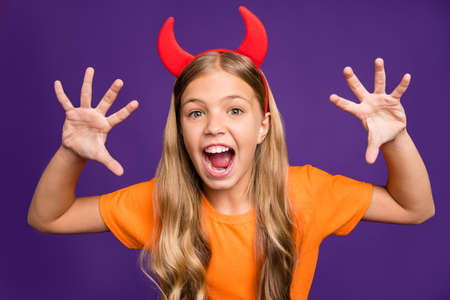 Boo. Photo of little lady headband horns head frightening facial expression, helloween party showing claws fangs wear orange t-shirt isolated purple color backgroundの写真素材