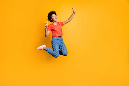 Full size photo of crazy beautiful funky curly hair girl blogger jump use, smartphone take selfie...