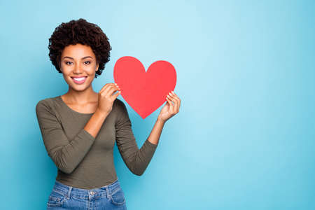 Portrait of positive dreamy dark skin girl hold big red paper card valentine, heart for 14-february...