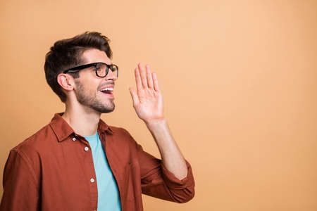 Close-up profile side view portrait of his he nice attractive cheerful cheery successful content brunette guy saying good news isolated over beige color pastel backgroundの写真素材