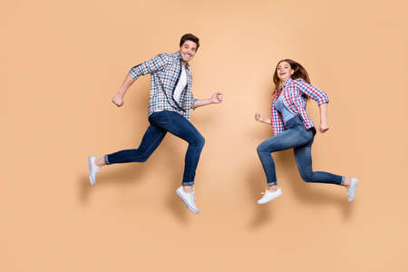 Full size profile photo of two people crazy lady guy jumping high opposite, rushing men's women's stores shopping wear casual clothes isolated beige backgroundの写真素材
