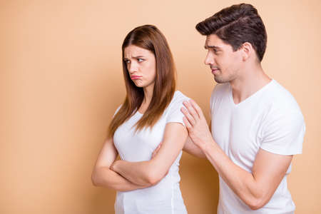 Close-up portrait of his he her she nice attractive couple wearing white t-shirt brunet guy supporting naughty red redhair girl isolated over beige pastel color backgroundの写真素材