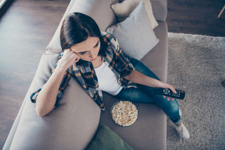 High angle view photo of pretty lady holding remote controller and popcorn plate upset of favorite serial ending sitting sofa wearing casual clothes apartment indoorsの写真素材