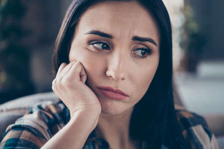 Closeup photo of pretty lady holding hand on cheek stressed with loneliness very sad expression sitting sofa wearing casual clothes apartment indoorsの写真素材