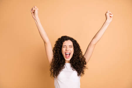 Photo of amazing yelling lady listening great advertising sale shopping triumphing raising fists wear white casual clothes isolated beige pastel color backgroundの写真素材