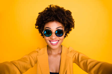 Close up photo of positive cheerful afro american girl make selfie feel content emotion son holidays wear stylish suit isolated over yellow color backgroundの写真素材