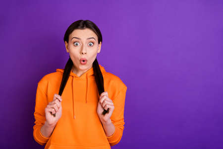 Close-up portrait of her she nice attractive lovely cute winsome cheerful amazed impressed girl touching ponytails isolated over bright vivid shine vibrant violet purple lilac color backgroundの写真素材