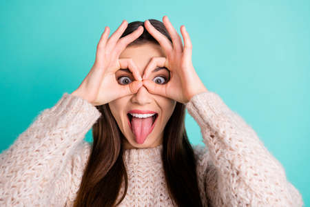 Close up photo of dreamy carefree girl making binoculars with her fingers fooling having fun wear...