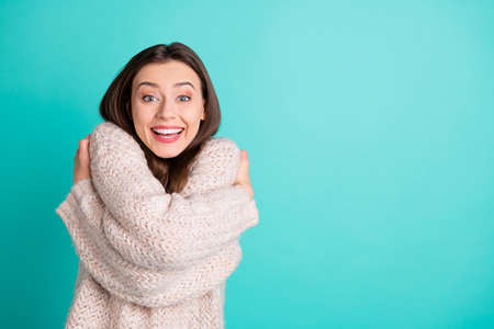 Portrait of crazy funky girl hug herself impressed by quality warm soft pullover scream wow omg isolated over teal turquoise color backgroundの写真素材