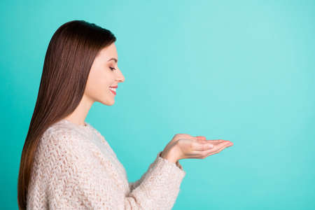 Photo of charming cute fascinating dreaming girlfriend holding something, nice with her hands wearing knitted sweater while isolated over turquoise color bright backgroundの写真素材