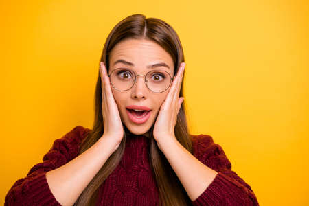 Close up photo of funky lady touching her cheeks shouting unbelievable wearing marsala sweater isolated over yellow backgroundの写真素材